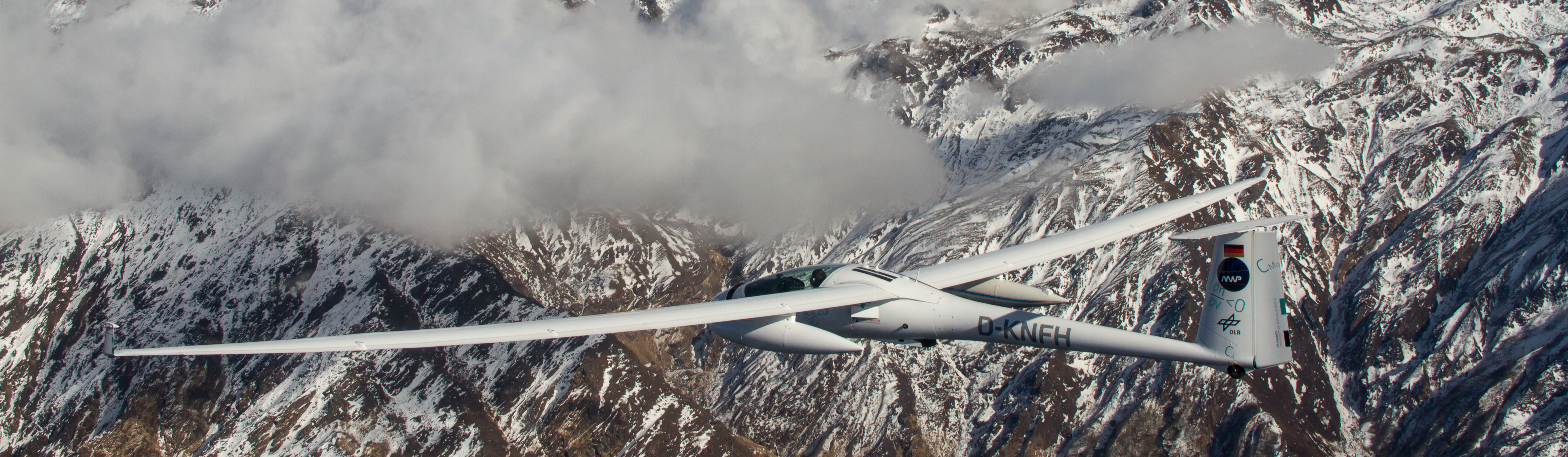 D-KNFH sailplane gliding past a snow-capped Himalayan ridge, seen from a chase aircraft.