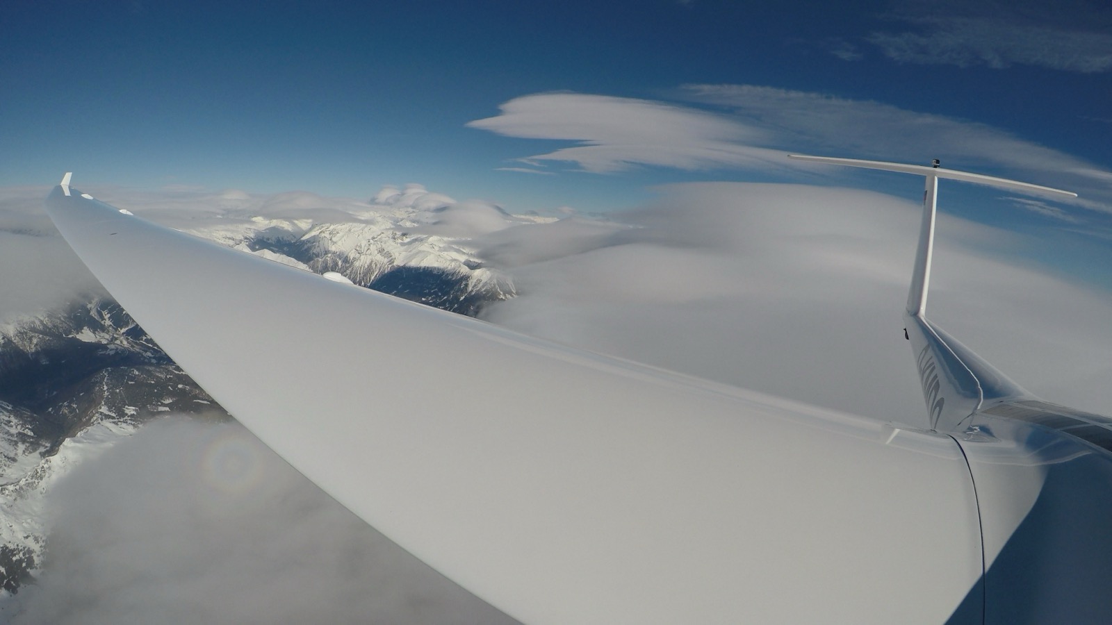 Glider wing high above the Andes, mountain wave clouds in the distance.